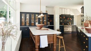 navy blue kitchen with large freestanding kitchen island and glass fronted units