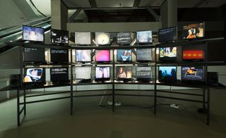 Three rows of eight televisions displaying sci-fi television programmes and traditional Chinese Opera.