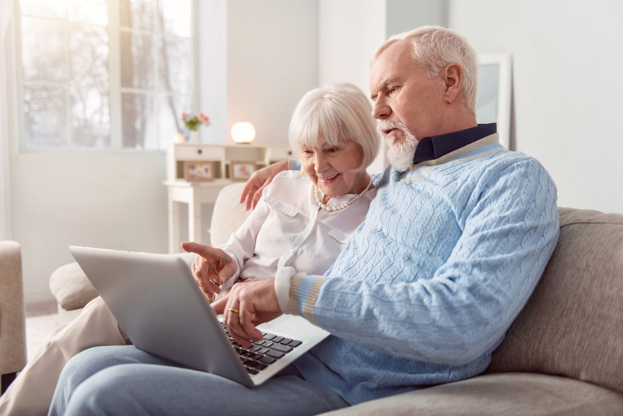 Couple sitting on the couch in the living room and looking at laptop,