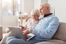 Couple sitting on the couch in the living room and looking at laptop,