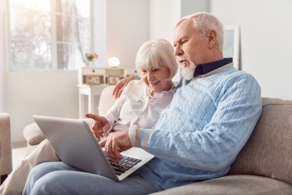 Couple sitting on the couch in the living room and looking at laptop,