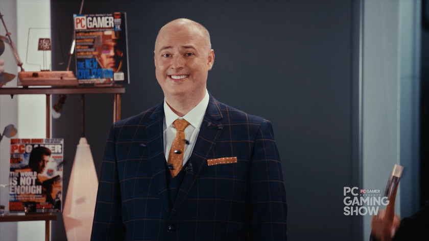 Sean Day9 Plott in a suit and tie with a shelf containing PC Gamer magazines behind him