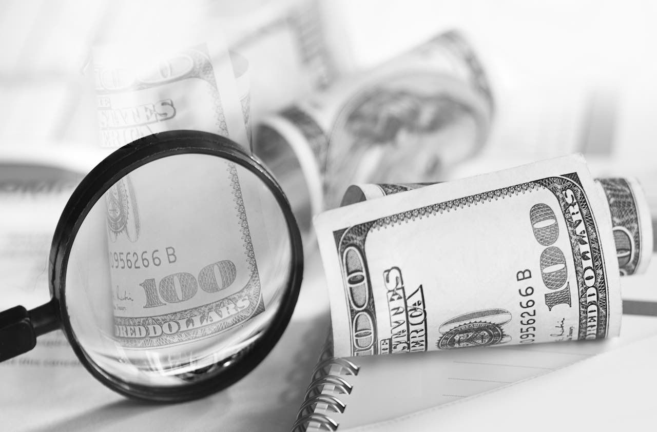 Image of selective focus shot of magnifying glass and hundred dollars bills