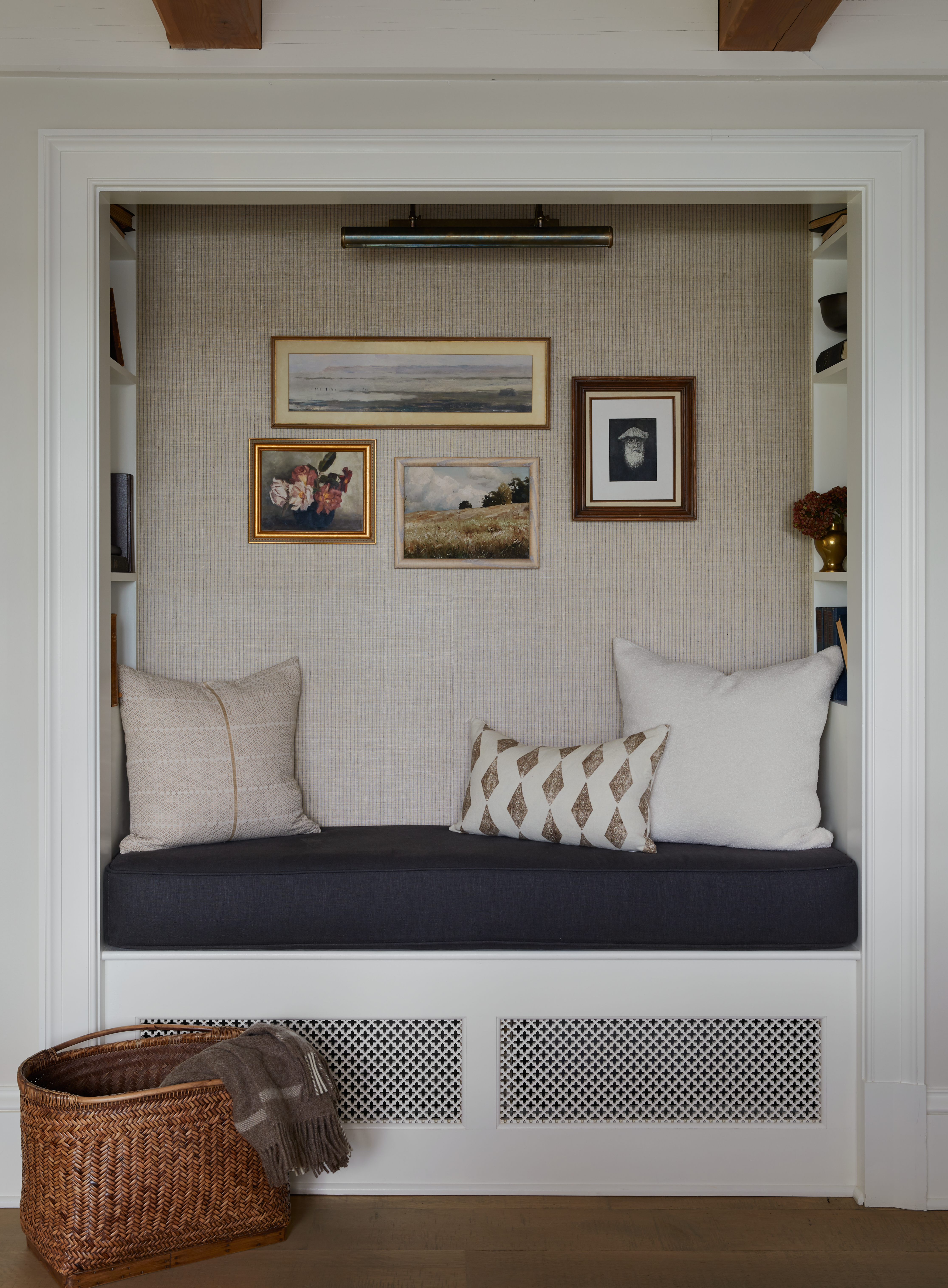 Sitting nook with antique-style artwork, a navy blue cushion, and a woven basket on the floor