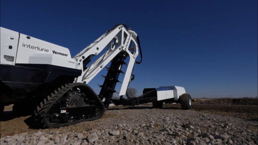 A large machine with tread wheels and a white body sits on a gravel path.