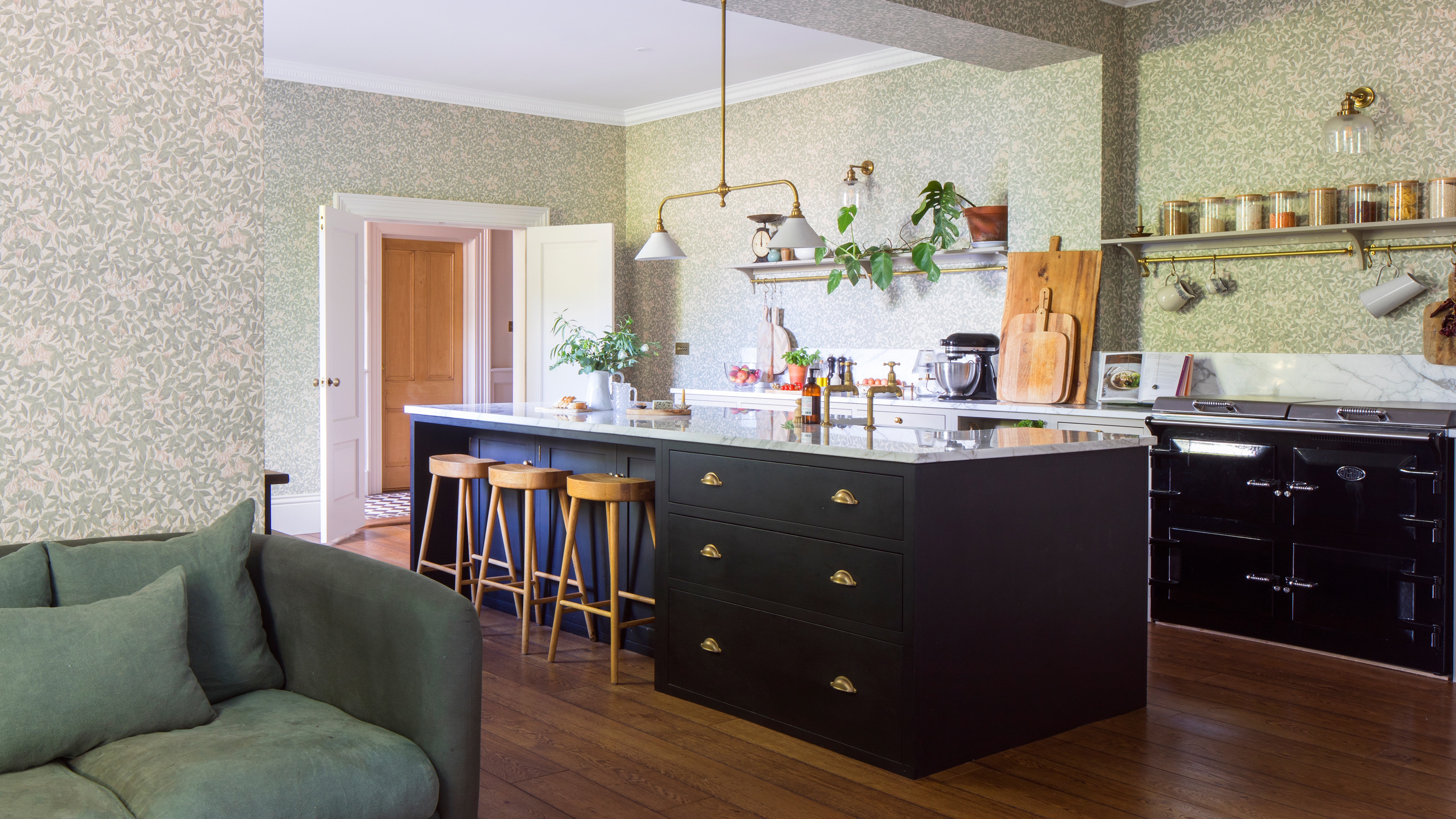 an open plan country-style kitchen with opening shelving, a black Aga and a kitchen island with three bar stools