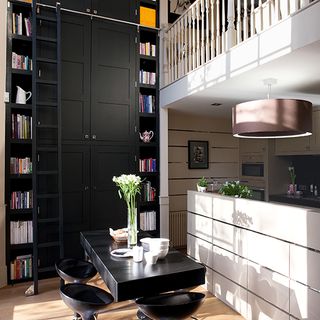 room with black dining table stool and black coloured double height cabinet