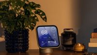 An Apple HomeView device on a side unit next to a pot plant, stack of books and some keys.