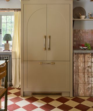 red and cream traditional checkerboard floor in a cottage kitchen with a pale yellow fridge cabinet