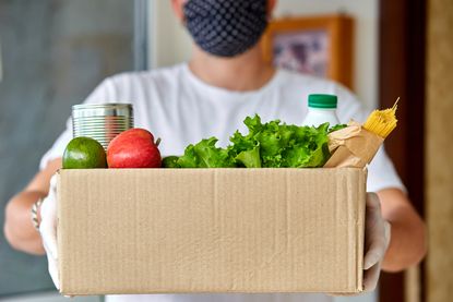 A person holds a box of groceries.