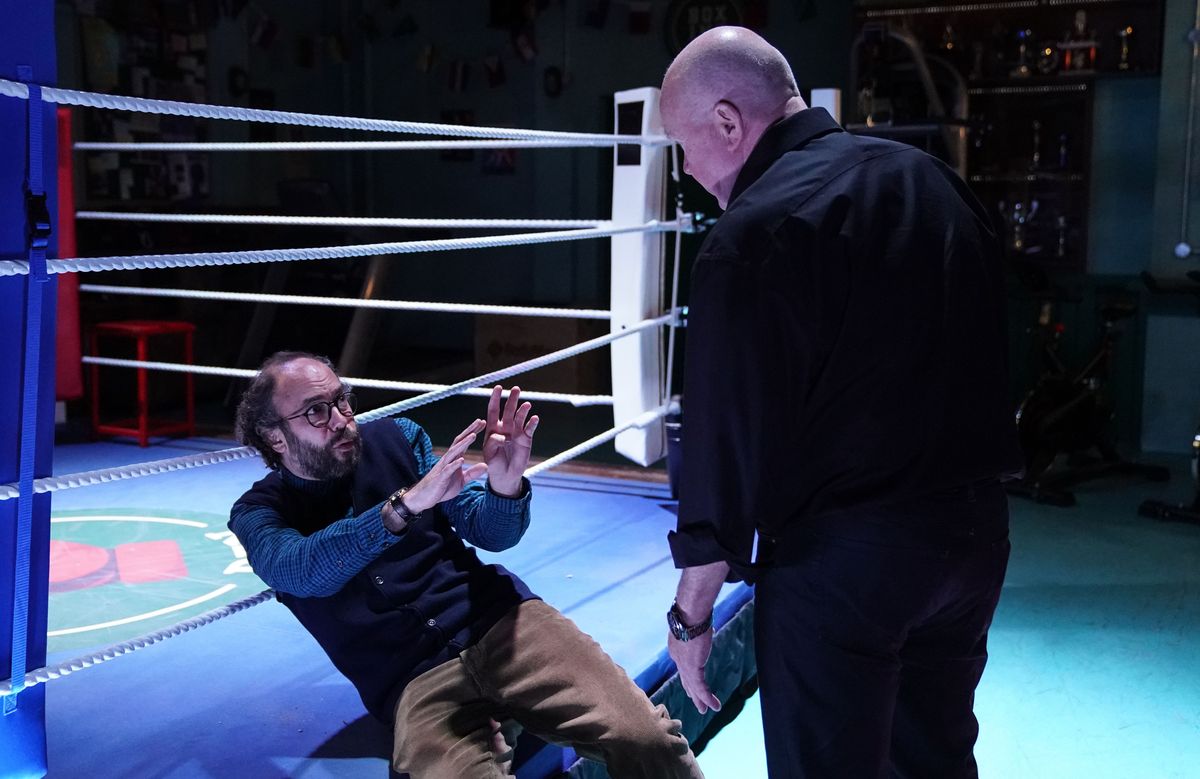 Reiss Colwell lying back on a boxing ring being threatened by Phil Mitchell