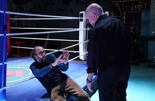 Reiss Colwell lying back on a boxing ring being threatened by Phil Mitchell