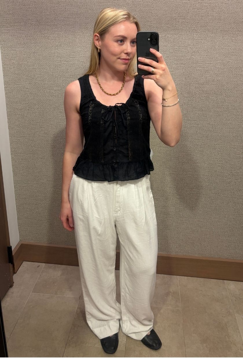 Woman wears black blouse, white linen trousers, black ballet flats