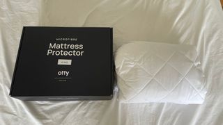 OTTY Waterproof Mattress Protector next to its box on the bed