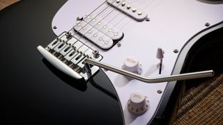 Sterling By Music Man Intro Series Cutlass: the entry-level double-cut electric is finished in gloss black, has a three-ply white pickguard and a maple fingerboard with black dot inlays.