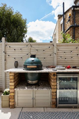 An outdoor kitchen with a big green egg barbecue grill and festoon lights