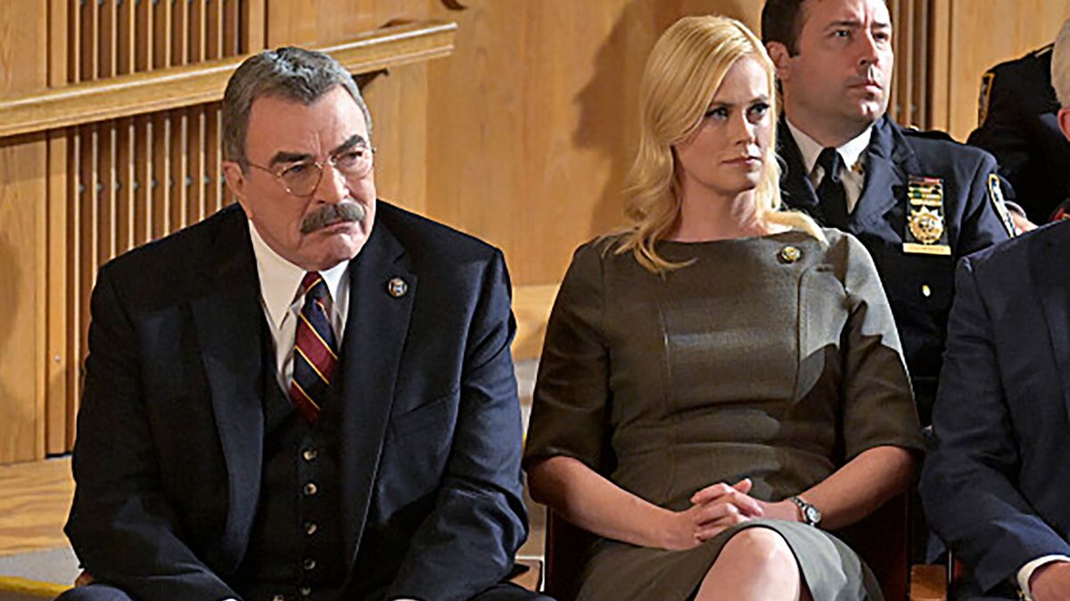 Abigail Hawk and Tom Selleck as Reagan family members in Blue Bloods courtroom scene. 