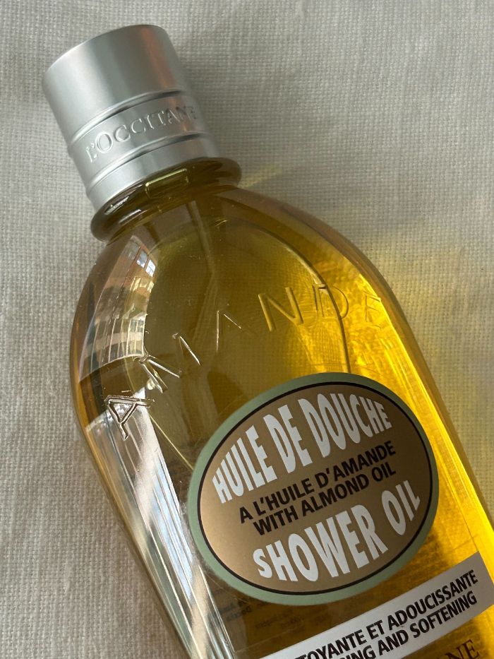 A picture of the L'Occitane Almond Shower Oil on a white linen background