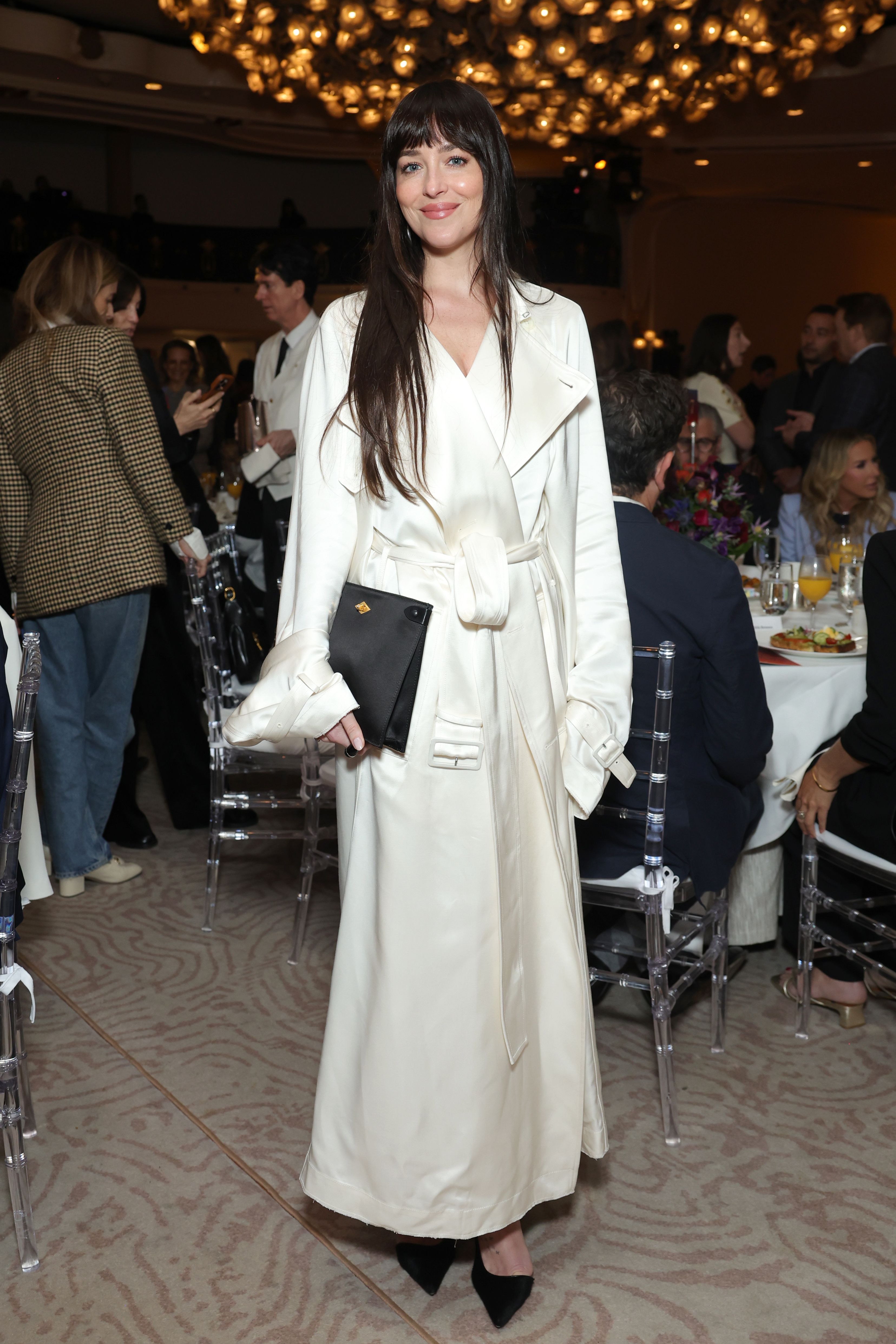 Dakota Johnson delivered holiday party dressing inspiration in a white satin trench coat