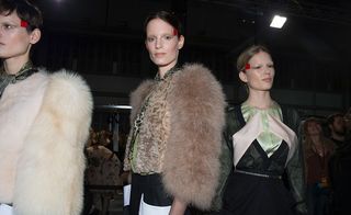 3 female models lining up for runway wearing fur coats