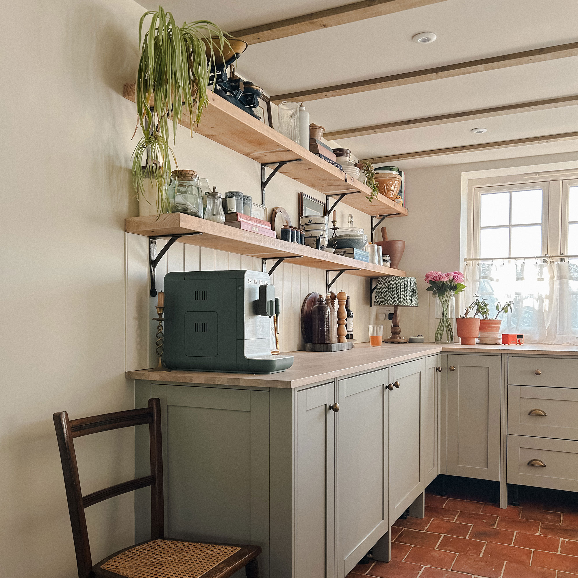 Corner of kitchen with Shaker cabinetry, coffee machine and open shelving