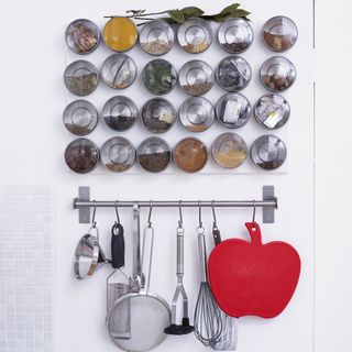 Back of a white kitchen door used to hang utensils and magnetic spice jars