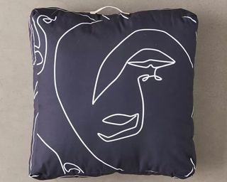 A black and white outdoor cushion with line art facial graphic motif