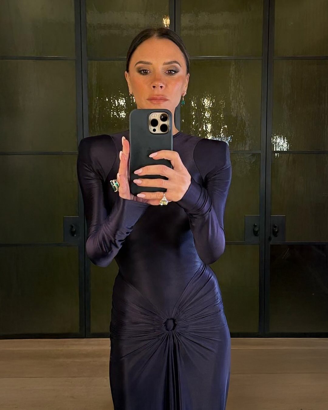 A photo of Victoria Beckham taking a selfie in the mirror wearing a purple dress