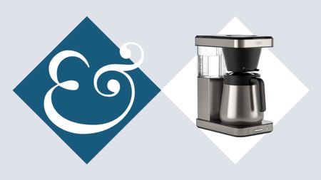 A stainless steel drip coffee maker on beside a blue diamond with an & sign in it. 