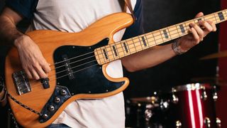 Man playing a fretted bass guitar