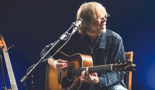 Trey Anastasio plays an acoustic guitar onstage