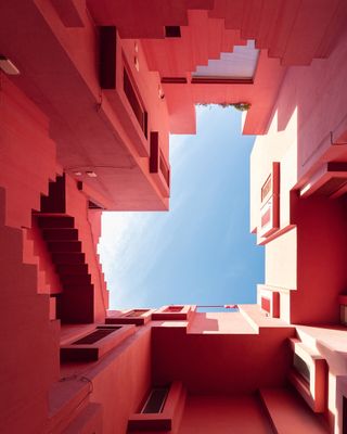 View from below of pink exterior walls and stairs at La Muralla Roja by Ricardo Bofill in Calp, Spain