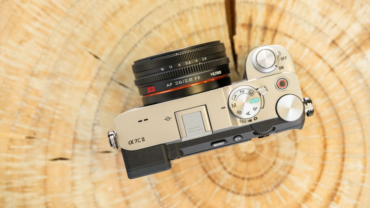 Viltrox AF 26mm F2.8 EVO lens attached to a Sony camera, top down, resting on a tree stump