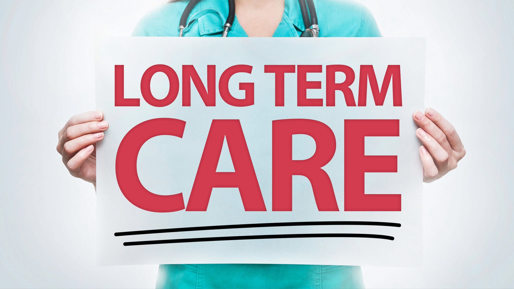 Close up of a health worker in scrubs holding up a sign reading Long Term Care