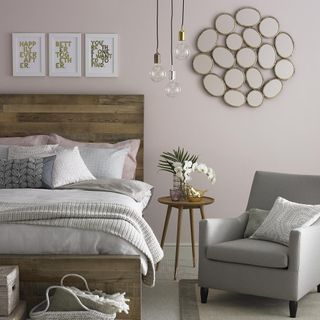 Light pink bedroom with grey armchair and bedside table