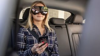 Junge Frau sitzt auf dem Rücksitz eines Autos, während sie ein VR-Headset trägt
