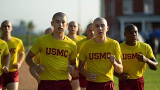 (L to R) Liam Oh as Ray McAffey and Miles Heizer as Cameron Cope in front of other recruits, running as part of their boot camp, wearing yellow USMC t shirts and red shorts