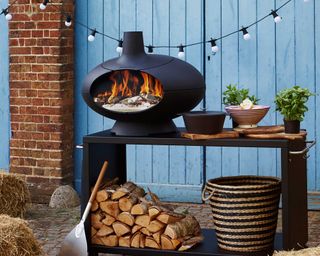 outdoor wood-fired oven with a stack of logs underneath