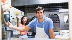 A man running a lunch counter looks exasperated as his wife throws her hand up in frustration.