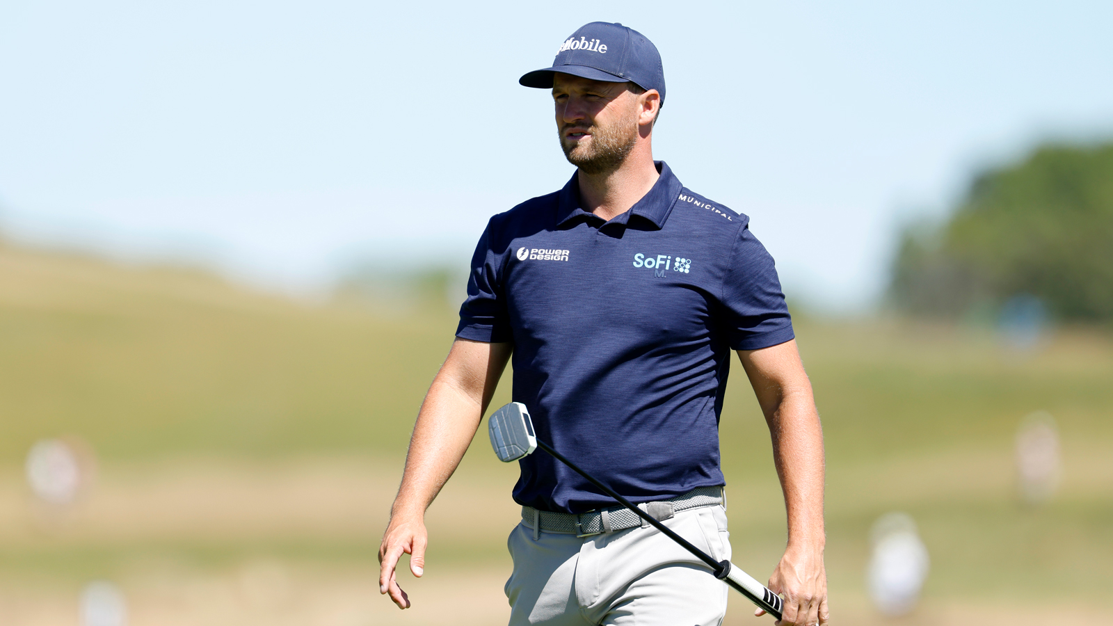 Wyndham Clark walks off the green holding a putter