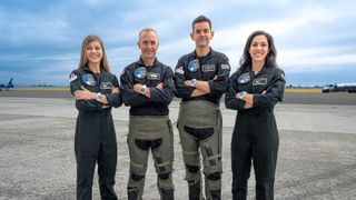 The crew of Polaris Dawn pose in front of a fighter jet.