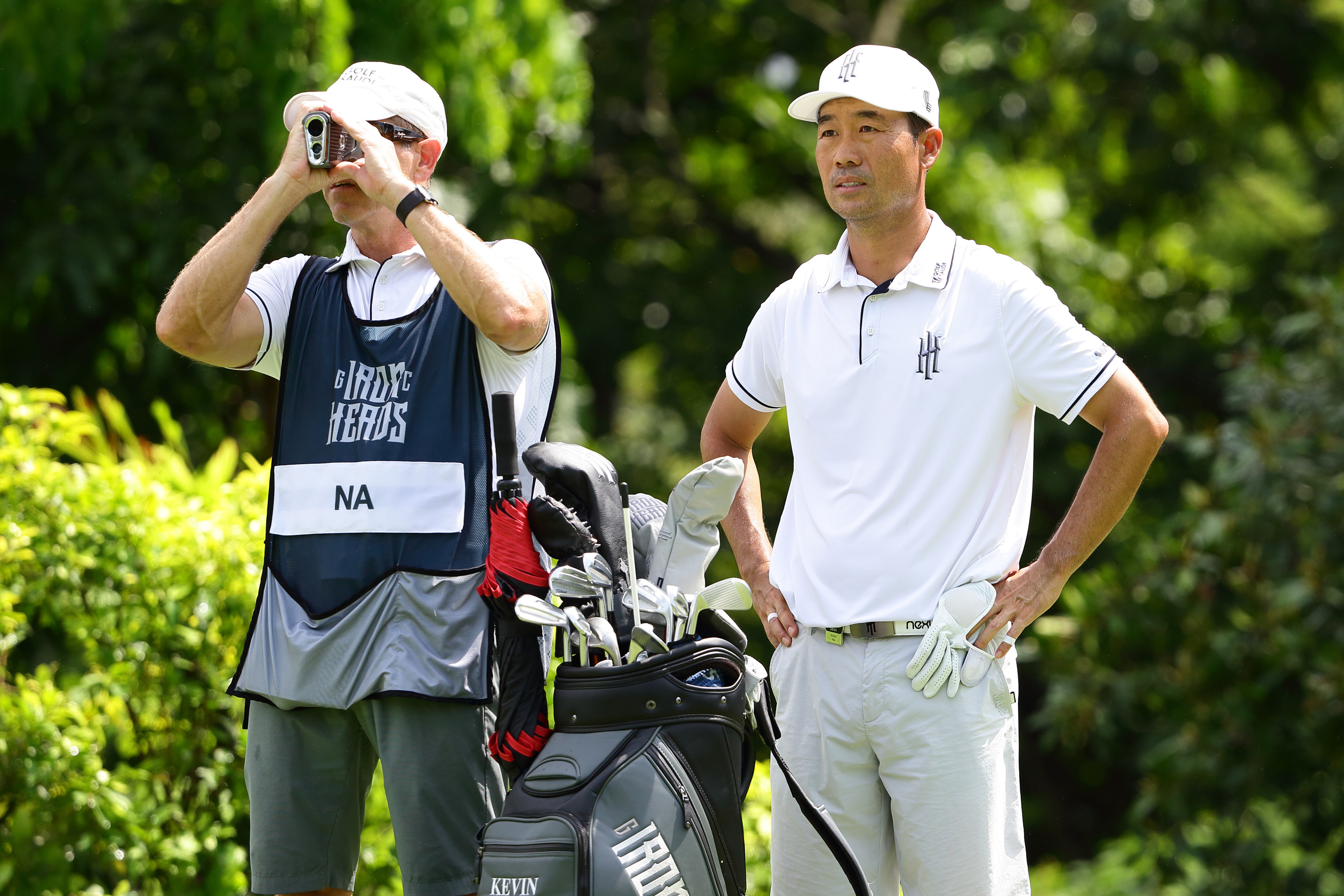 Kenny Harms uses a rangefinder, while Kevin Na watches on