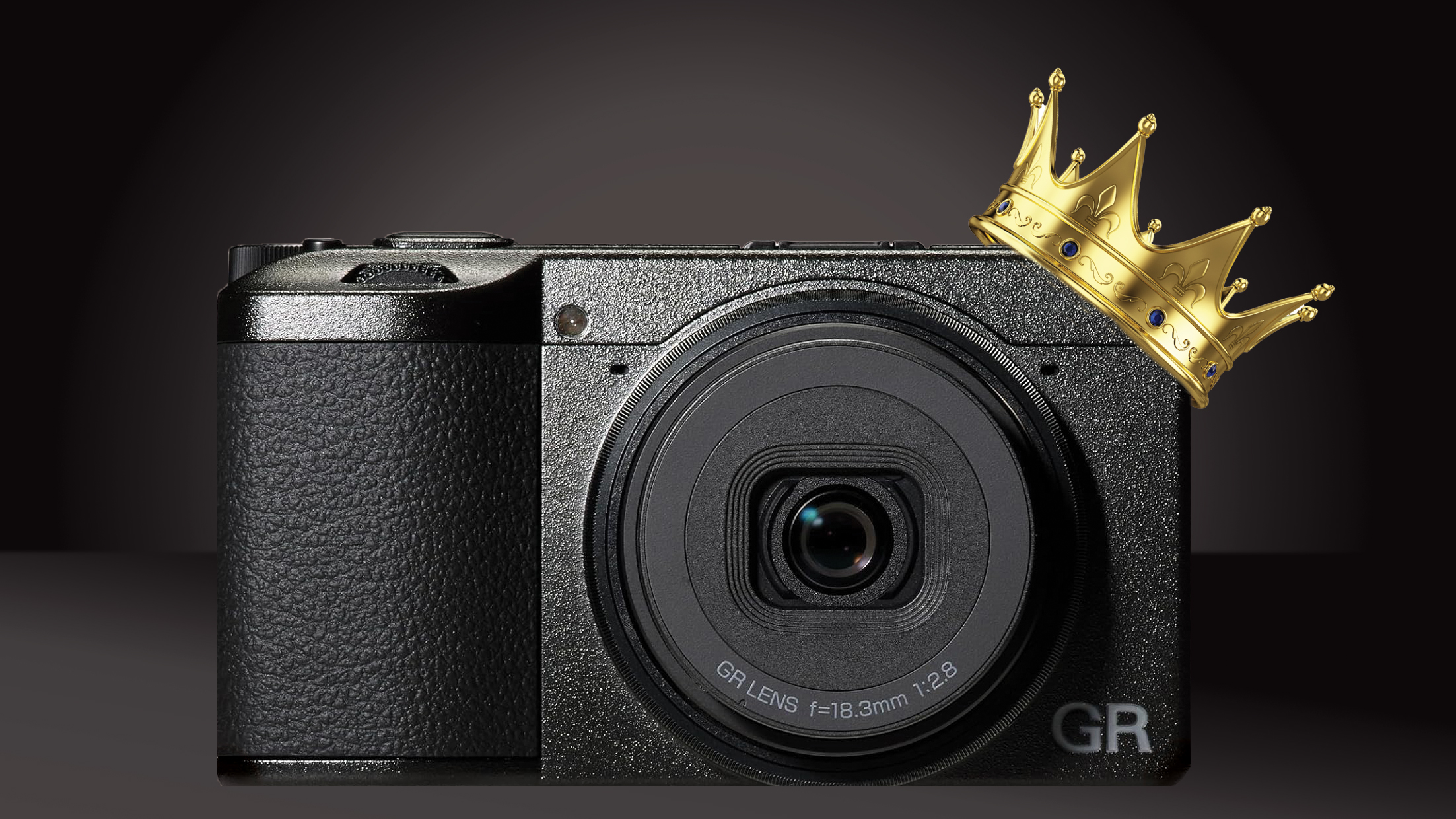 A stylish Ricoh GR IV compact camera with a gold crown on top, set against a rich black backdrop