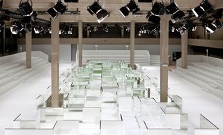 Large show space at the Tennis Club de Paris in white, with a mirrored labyrinth guiding the models' path