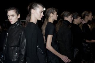 Female models standing behind each other wearing black