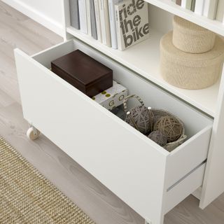 Birds eye view of a white bookcase with an opened wheel out drawer at the bottom