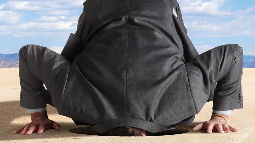 Man in a suit with his head in the sand