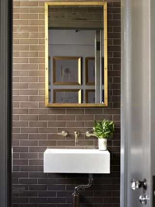 white wall hung sink on brick wall in bathroom by BHDM