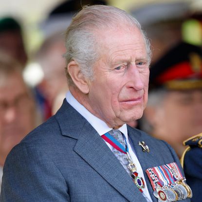 King Charles wears a blue suit with military medals attached and he looks very sad