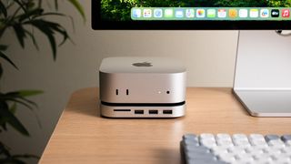 The Mac mini M4 on top of Satechi's new Mac Mini Hub on a desk underneath an Apple Studio Display with a mechanical keyboard on a desk